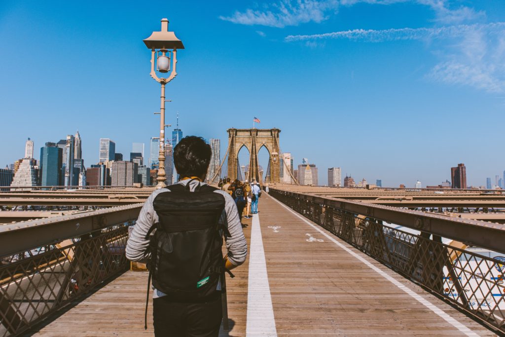 man walking over the brooklyn bridge