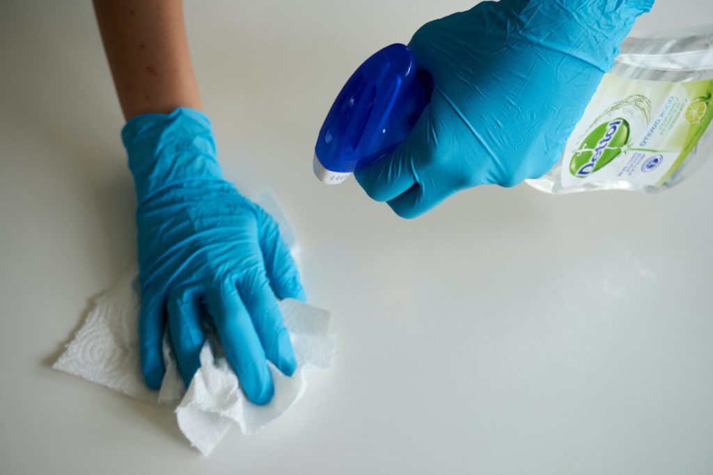 gloved hands cleaning surface
