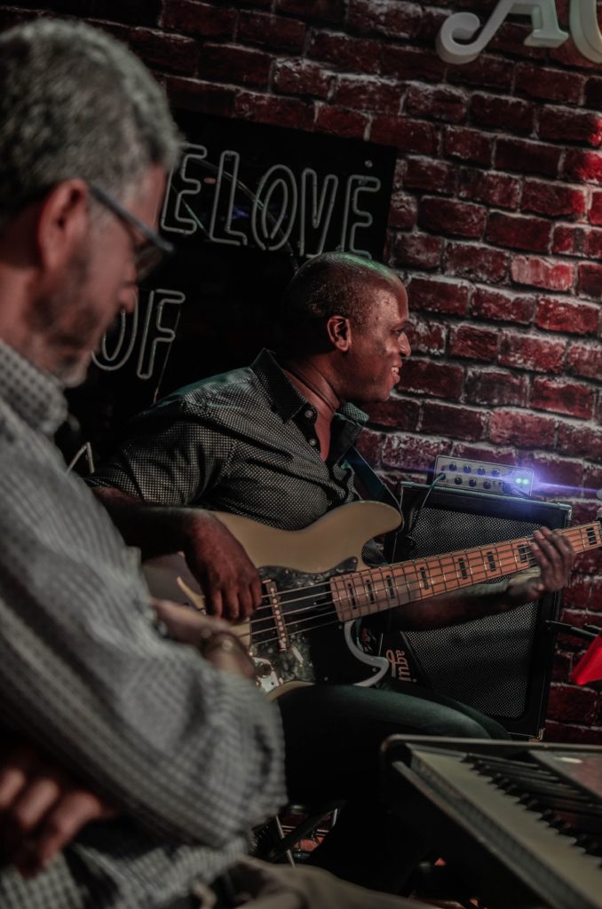 men on a small stage in a brick walled room playing jazz