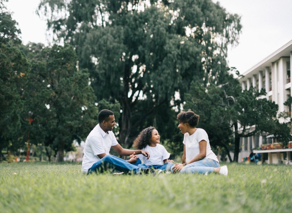 family sitting on the grass together in an urban setting